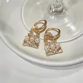 Dettaglio di eleganti orecchini di perle a forma di borsa con cristalli lucidi - Stile Borsa (HE33919) / Fibbia per orecchie / Oro