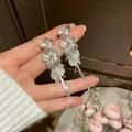 Detailed close-up of silver floral tassel earrings with white petal accents - Silver
