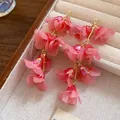 Close-up of elegant pink organza flower petal drop earrings in a beige jewelry box - Pink