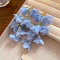 Macro view of multi-layered blue fabric flower petals on bohemian style earrings - Blue