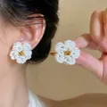 Dettaglio di orecchini a forma di camelia in perle bianche fatti a mano. - Stud orecchini / Bianco