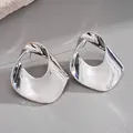 Macro view of irregular hollow silver earrings with high-gloss metallic finish - Silver