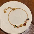 Close-up detail of a French retro gold-plated bracelet with colorful zircon flower charms. - Gold (Multicolor Inlaid)
