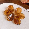 Macro detail of amber marble resin flower stud earrings with gold floral centers - Brown