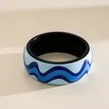 Macro shot of a glossy resin bangle featuring a vibrant blue wavy ocean pattern. - Dark Blue Wave / Blue