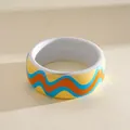 Close-up of colorful resin bangle with wave pattern in blue, orange, and yellow - Yellow Blue Wave Pattern / White