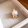 Close-up of a wide gold band ring featuring a large white pearl in a jewelry box - Gold