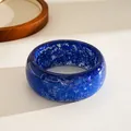Macro detail view of blue resin bangle with shiny star and snowflake glitter patterns - Blue