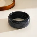 Close-up showing the shimmering glitter star detail on this round resin bangle bracelet - Black