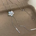 Gros plan d'un pendentif fleur argenté serti de cristaux sur un collier à pampilles en maille - Collier à Gland de Fleur / Argent