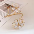 Detailed view of the elegant gold-tone metal arm cuff featuring white enamel flowers. - Bangle / Gold White