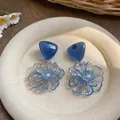 Detailed view of handmade blue resin flower earrings with pearl accents on plate - Flower (HE33458) / Blue