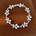 Elegant silver bracelet with purple and white flower-shaped zircons on brown texture. - Silver-Purple