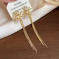 Detailed close-up of firework tassel earrings with pearls and gold plating - Gold