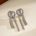 Primo piano di eleganti orecchini a nodo con lunghe nappe di strass brillanti in argento - Argento