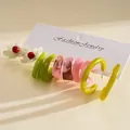 Detail of a 10-piece resin earring set with marble and floral geometric C-shaped designs. - Pink and Green Ten Piece Set