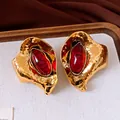 Dettaglio di orecchini vintage dorati con pietre ovali in resina rossa e design a foglia. - Oro-Rosso