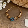 Detailed view of the gold-plated flower necklace with a central blue enamel blossom - Necklace / Gold-Blue