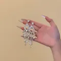 Close-up of sparkling silver needle rhinestone tassel earrings for banquet and party wear. - Silver