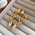 Close-up of golden geometric hollow metal earrings on a gray velvet tray - Silver Needle / Gold