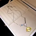 Primo piano del ciondolo a testa di cane in resina e zirconi su catena d'argento nel portagioie - Ciondolo Testa di Cane e Osso / Giallo
