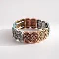 Detail shot of vintage multi-color metallic elastic bracelet with intricate floral carvings - Colorful