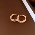 Close-up of 18k gold plated wrinkled hoop earrings showing fine texture and metallic luster. - Huggie Earring (HE33971) / Gold