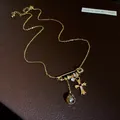 Vue macro d'un pendentif épingle de sûreté plaqué or 18k avec croix en zircone - Collier(HN12195) / Or
