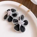 Detailed macro shot of vintage black gauze flower earrings featuring lustrous pearl centers - Black