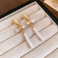 Detail shot of vintage gold drop earrings featuring unique natural freshwater pearls - Gold-White