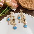 Detail view of blue enamel ocean-themed drop earrings with starfish and fish pendants - Silver Earring Post - Gold - Blue