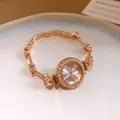 Nahaufnahme einer roségoldenen Damenuhr mit funkelndem, strassbesetztem Blumenarmband - Armband-Uhrenarmband / Gold