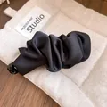 Elegant black satin-like twist hair clip detail shown on a beige quilted fabric pouch - Single Piece / Banana Clip-Black-1 Piece
