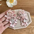 Detail view of pink petal flower tassel earrings with white seed bead dangles on fabric - Flower Tassel Style (HE32829) / Pink