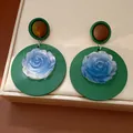 Detailed view of vintage resin earrings featuring a blue rose center on a green round base - Silver Earring Post Style / Green/Blue