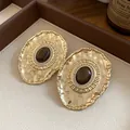 Detailed macro view of vintage palace style gold oval stud earrings with crystal halo - Silver Post Oval Style / Gold & Coffee