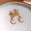 Gros plan de boucles d'oreilles dorées de style français avec motifs lune et soleil en strass - Boucles d'oreilles gouttes / Or