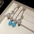 Macro view of vintage rhinestone leaf drop earrings in white and blue pearl finish - Silver