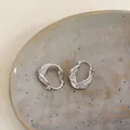 Close-up of twisted hollow geometric ear buckles with sparkling cubic zirconia stones - Twisted Hollow Geometric Style (HE32351) / Silver
