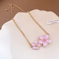 Macro detail view of pink enamel flower pendants on a gold-plated necklace chain. - Choker Necklace / Pink