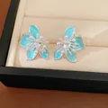 Close-up view of blue enamel flower stud earrings with heart-shaped zircon and pearls - Silver-Blue