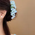 Close-up view of a light blue floral hair pin worn on a model in an elegant style - Blue Style (HH9871) / 1 Piece / Blue