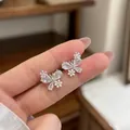 Nahaufnahme von zarten Schmetterling- und Blumenohrsteckern mit Zirkonia-Akzenten. - Schmetterling-Blumen-Stil / Silbernadel / Silber