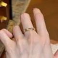 Detailed view of a gold-tone leaf open ring with colorful zircon stones on a hand. - Multicolor Zirconia Open Ring / Gold