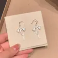 Detailed macro view of silver bow earrings with elegant sparkling zircon tassels - Bowknot Tassel (HE33136) / Silver