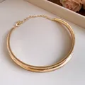 Detailed view of the elegant golden twisted metal choker necklace on a white surface - Pleated Crisscross Style (HN12048) / Gold