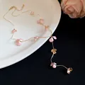 Close-up of elegant pink flower petal tassel necklace presented on a white ceramic plate - Gold, Pink