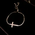 Dettaglio di un bracciale con croce dorata e zirconi scintillanti su velluto nero. - Braccialetto (HB5449) / Oro