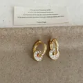 Close-up of gold hoop earrings with pave zircon round pendants and textured hoops - Round Pendant Ear Buckle / Gold