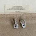 Detailed macro view of silver hoop earrings featuring sparkling round zircon drop pendants. - Round Pendant Ear Buckle / Silver